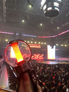 a person holding a light up in front of an audience at a convention or show