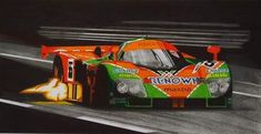 an orange and green race car with flames coming out of it's tires on a track