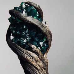 a piece of wood that has some green crystals on it and is sitting in front of a white wall