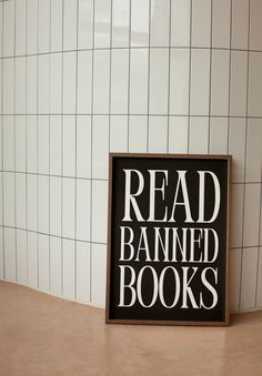 a sign that reads read banned books on the floor in front of a tiled wall