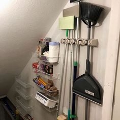 there is a rack with brooms and cleaning supplies on the wall next to it