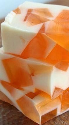 three pieces of soap sitting on top of a wooden table with orange and white squares