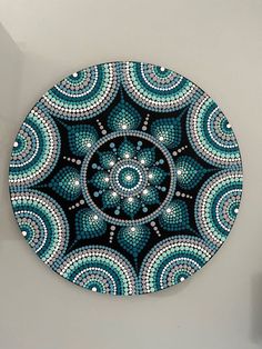 a blue and white circular design on the wall in front of a mirror with beads