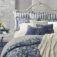 a bed with blue and white comforters in a room next to a brick wall