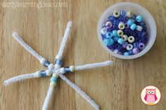 beads are arranged in the shape of a star on a wooden table next to a cup