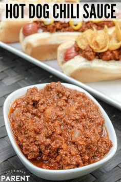 hot dog chili sauce in a white bowl next to two hot dogs on buns