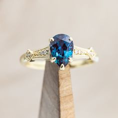 a blue diamond ring sitting on top of a piece of wood