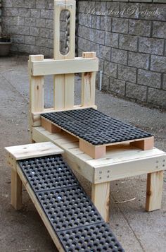 a chair made out of wooden pallets and some sort of step stool that is attached to a brick wall