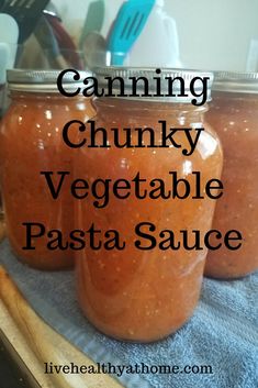 canning chunky vegetable pasta sauce in jars on a towel with spoons and utensils