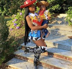 a woman holding a baby in her arms while standing on some steps wearing pirate costumes