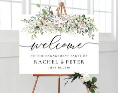 a welcome sign with flowers and greenery on it