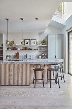 a kitchen with two bar stools next to an island in the middle of it