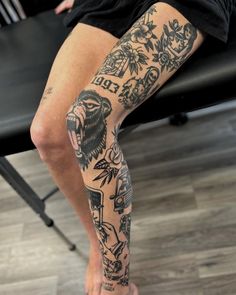 a person with tattoos on their legs sitting in front of a desk and chair,