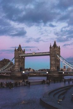 the tower bridge is lit up at dusk