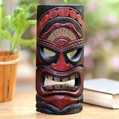 a wooden mask sitting on top of a table next to a potted green plant