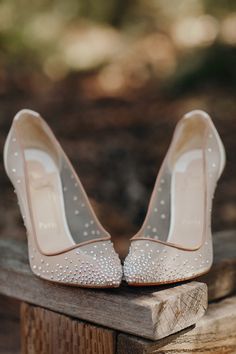 a pair of wedding shoes sitting on top of a wooden bench