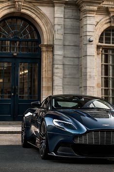 a blue sports car parked in front of a building with arched doorways and windows