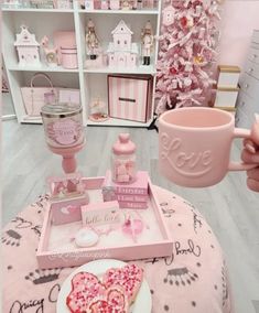 a pink table topped with a heart shaped cake next to a cup and saucer