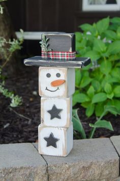 a snowman made out of blocks sitting on top of a brick wall