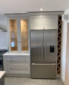 a stainless steel refrigerator in a kitchen with built - in wine racks and glass doors