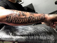 a man with a tattoo on his arm that says dream chaser in cursive writing