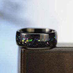 a black ring with multicolored glitters on it sitting on top of a wooden table