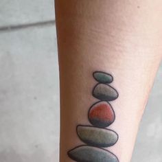 a woman's leg with a tattoo on it that has stones stacked on top of each other