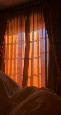 the sun is shining through the curtains on this bed in front of a window with drapes