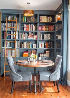 a dining room table surrounded by chairs and bookshelves