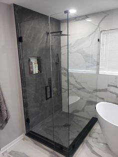 a white bath tub sitting next to a shower in a bathroom on top of a marble floor