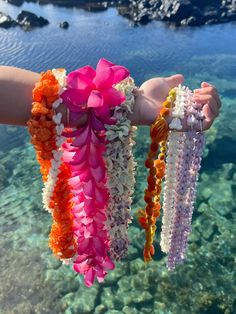 a person is holding some colorful leis in their hand over the clear blue water