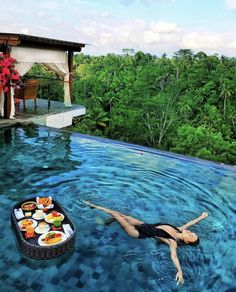 a woman laying on the edge of a swimming pool next to a table with food