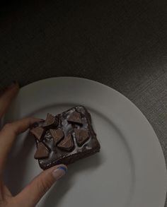 a person holding a piece of chocolate cake on a plate