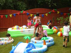 several children playing in an inflatable pool with floats and water toys on the lawn