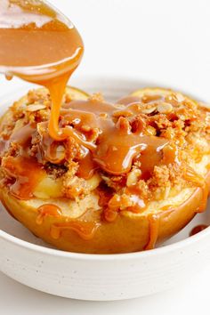 caramel sauce being drizzled on top of baked apples in a bowl