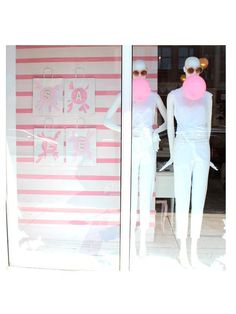 two mannequins in front of a store window with pink and white stripes