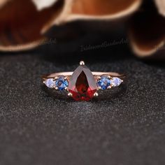 a close up of a ring with an orange and blue stone in the center on a black surface