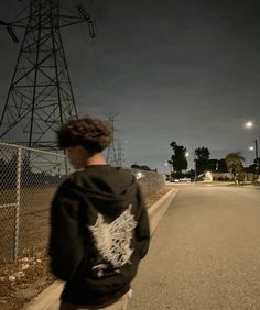 a young man riding a skateboard down a street next to a tall power line