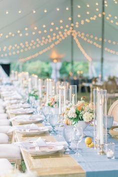 the tables are set with place settings and candles for an elegant dinner or reception in a marquee