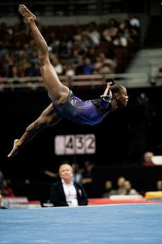 a woman is doing a trick on the balance beam