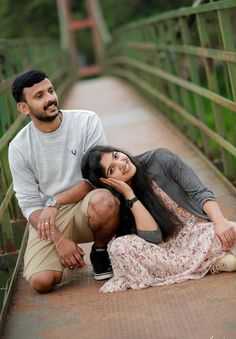 a man kneeling down next to a woman on a bridge while she holds her head