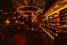 a dimly lit bar with lots of bottles on the shelves and lights hanging from the ceiling