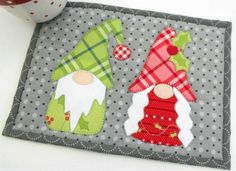 a close up of a patchwork place mat with gnomes and christmas decorations on it