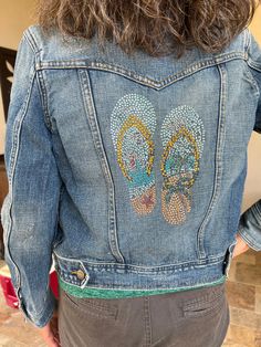 the back of a woman's jean jacket with sequins and butterfly patches