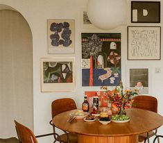 a dining room table with chairs and pictures on the wall in front of it,