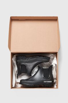 an open shoe box with black rubber shoes in it and the inside of its packaging