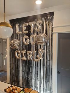 a table topped with lots of food next to a wall covered in disco balls and streamers