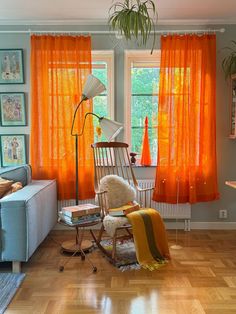 a living room with orange curtains and furniture