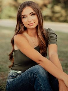 a beautiful young woman sitting in the grass