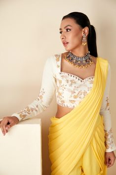 This ensemble boasts a pre-draped sharara saree in vibrant yellow and white hues, exuding elegance with every fold. Paired with a beautifully handcrafted blouse, featuring a sweetheart neckline and full sleeves, this ensemble epitomizes timeless grace. Crafted from luxurious georgette crepe, both the saree and blouse are meticulously designed for comfort and style. Elevate your ethnic wardrobe with this exquisite ensemble, perfect for special occasions and celebrations. Blouse And Sharara, White Blouse Designs, Sharara Saree, Full Sleeves Blouse Designs, Yellow Sharara, Latest Saree Blouse, Saree Blouse Styles, Latest Blouse Designs Pattern